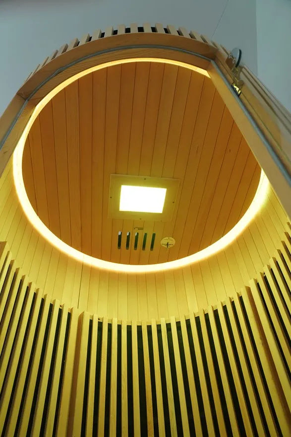 Top-down view of the circular hemlock wood ceiling and warm light inside the R Sauna Circle